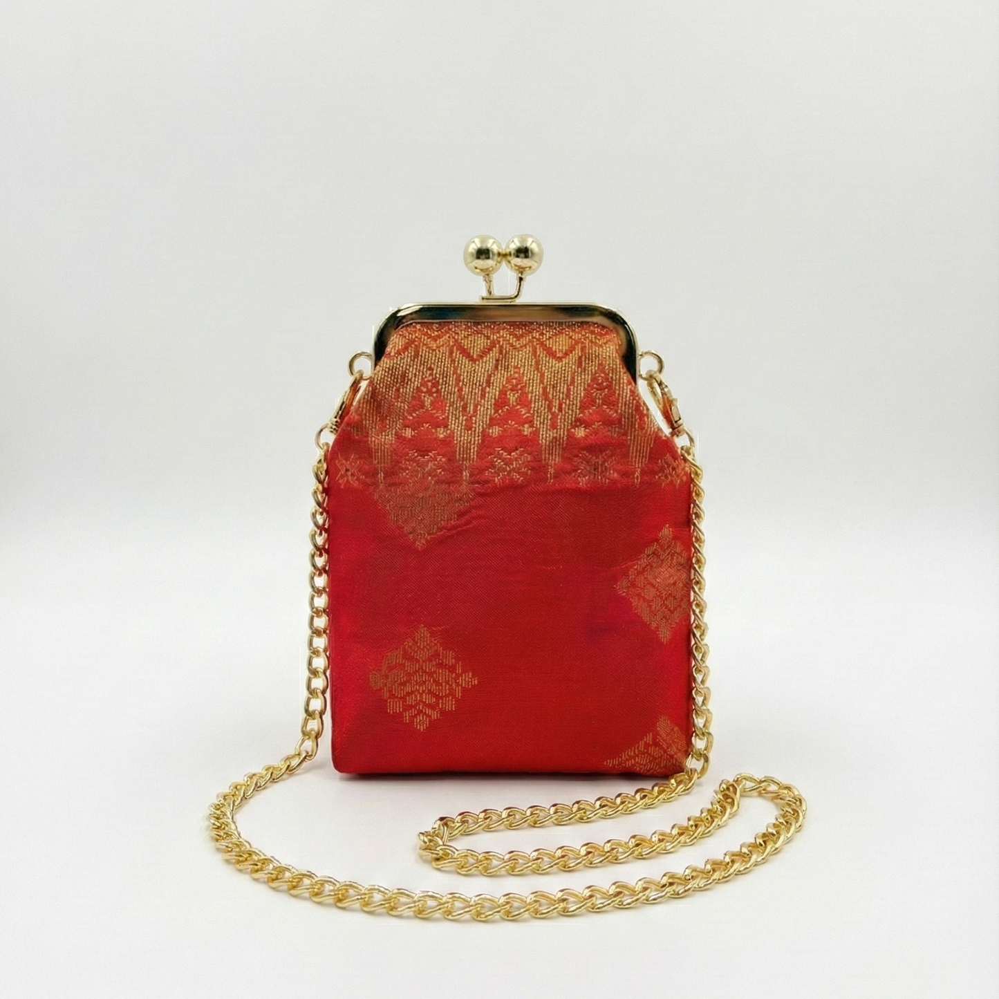 Red handbag with gold chain and intricate design on a white background