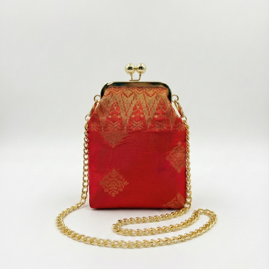 Red handbag with gold chain and intricate design on a white background